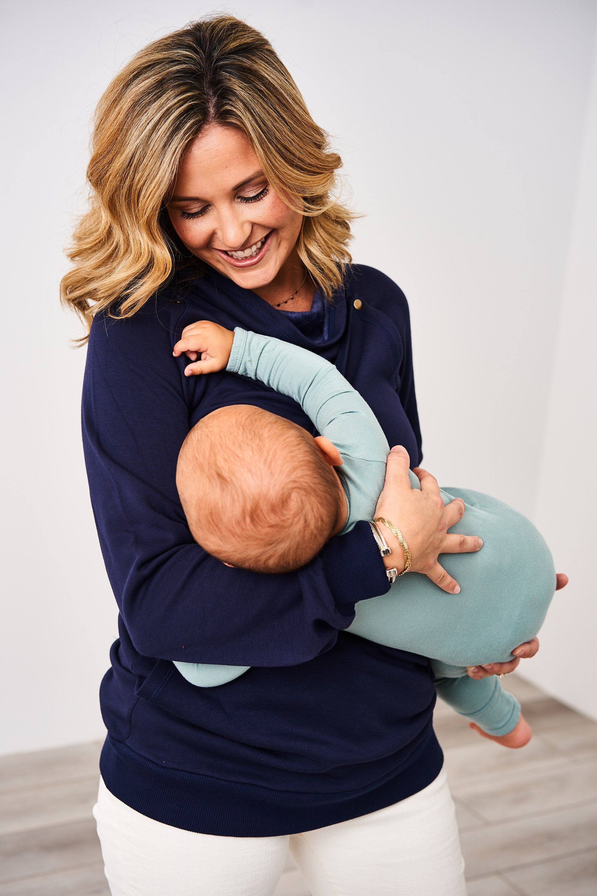 Woman nursing a baby in a Navy Latched Mama Harbor Snap Nursing Pullover
