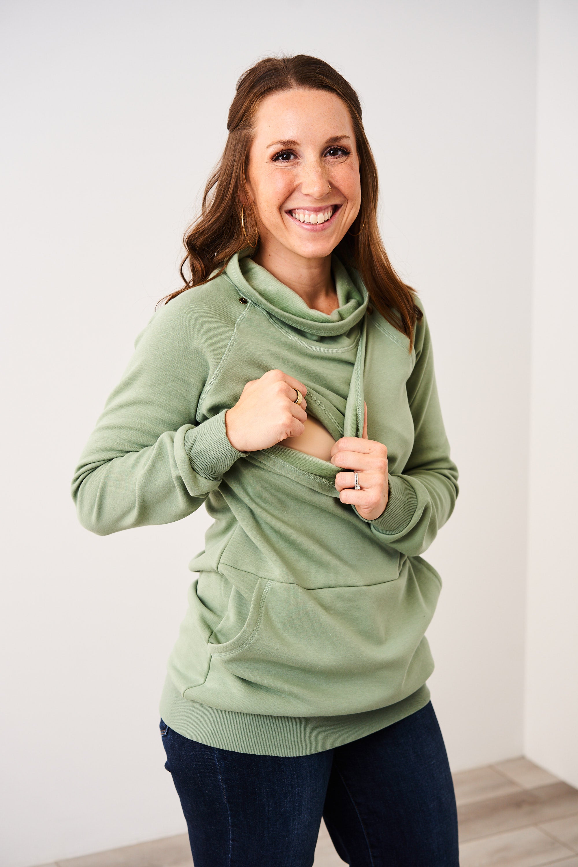 Woman showing the snap down nursing access of the Harbor Snap Nursing Pullover in basil
