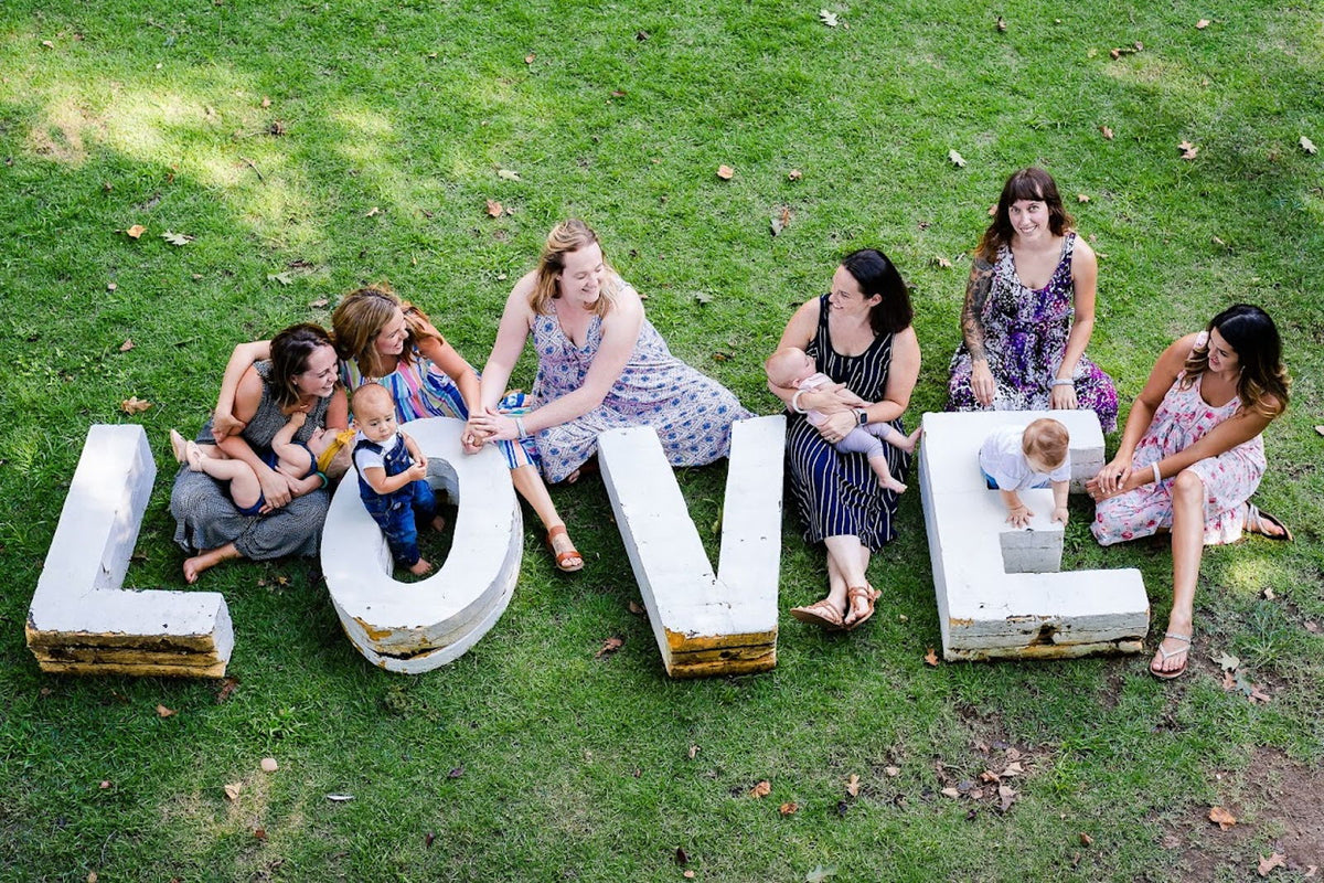 Mothers and children gathered around large letters spelling LOVE