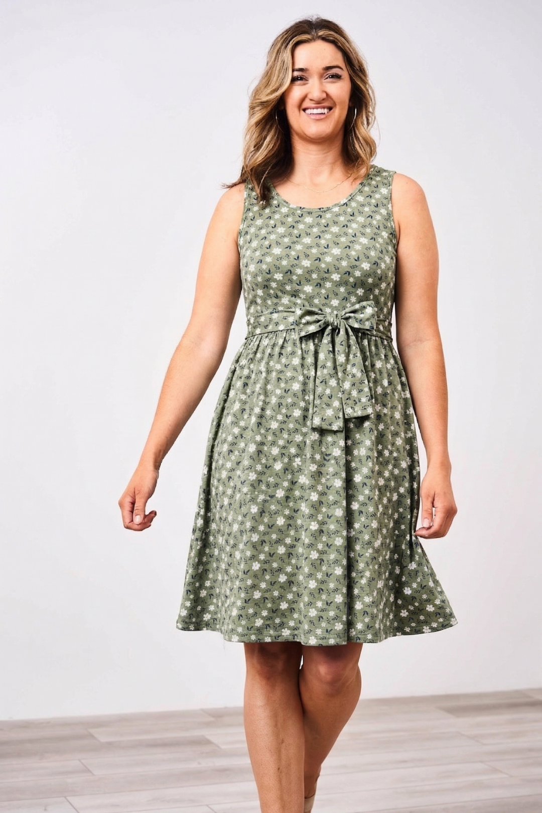 Woman wearing a green patterned floral Latched Mama nursing dress against a white background