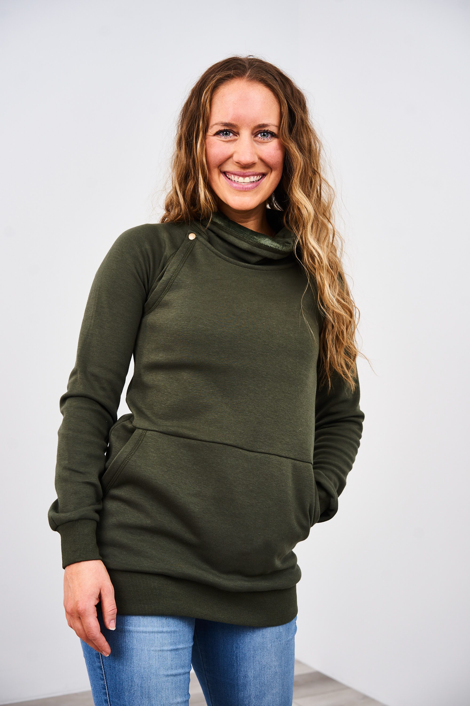 Woman wearing an olive green Latched Mama Harbor Snap Nursing Pullover against a white background