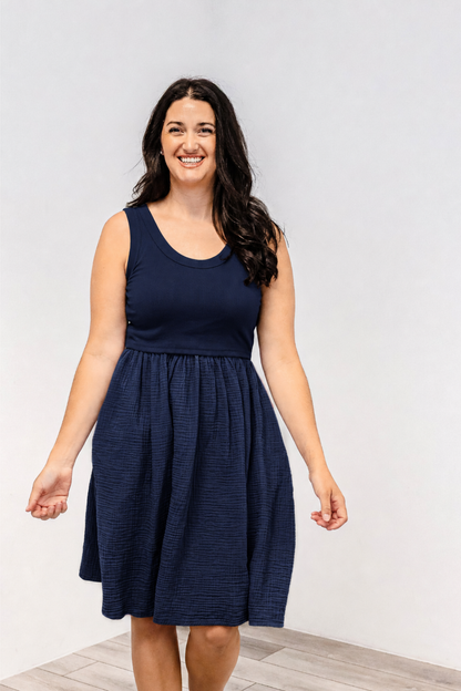 A woman wearing a tank top style cotton Latched Mama nursing dress in the color navy.