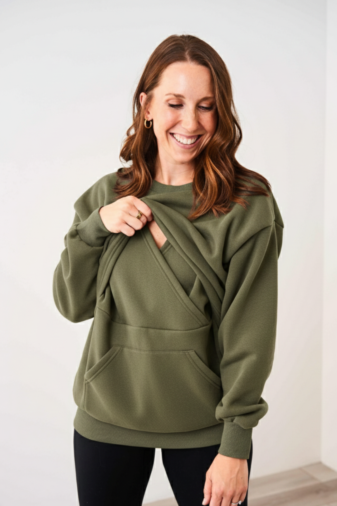 Mom showing discreet breastfeeding access on the Green Latched Mama Snuggle Up Nursing Pullover