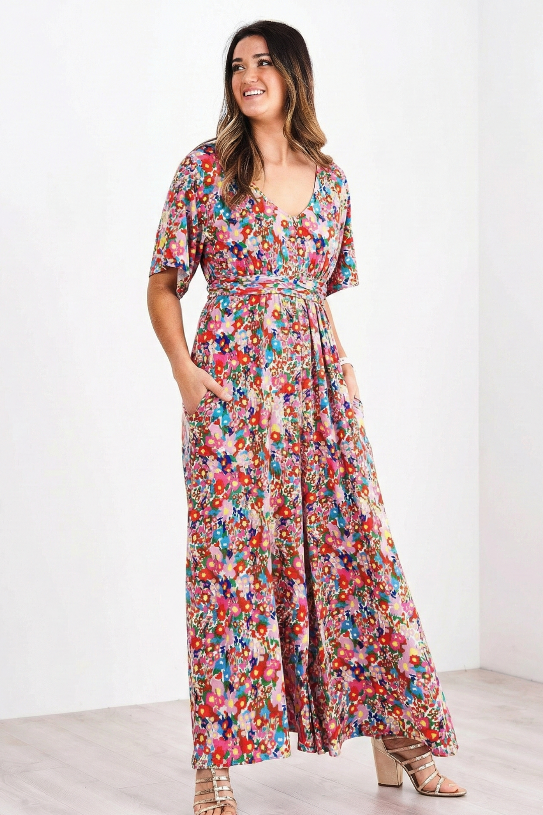 Woman wearing a colorful floral romper on a white background