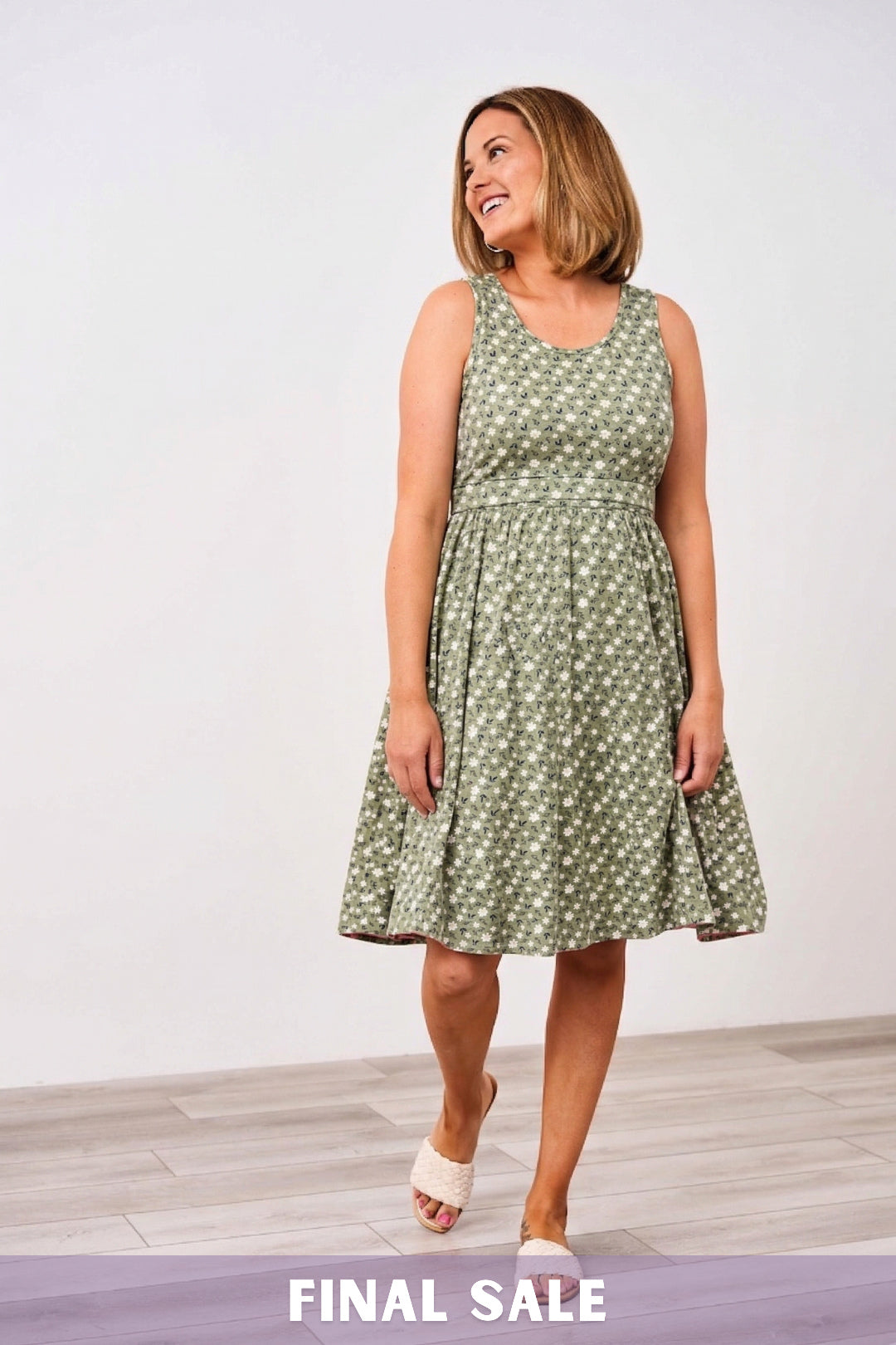 Woman wearing a green floral Latched Mama nursing dress against a white background