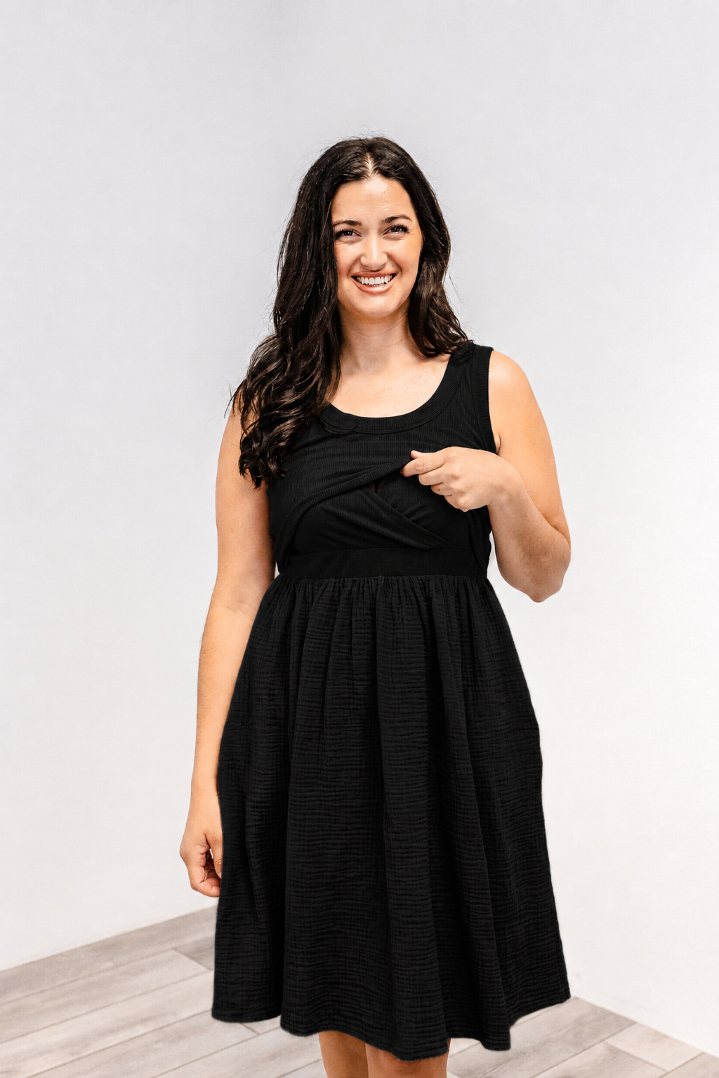 Woman showing the lift-up v-neck nursing access on the Latched Mama Breezy Cotton Nursing Dress in black.