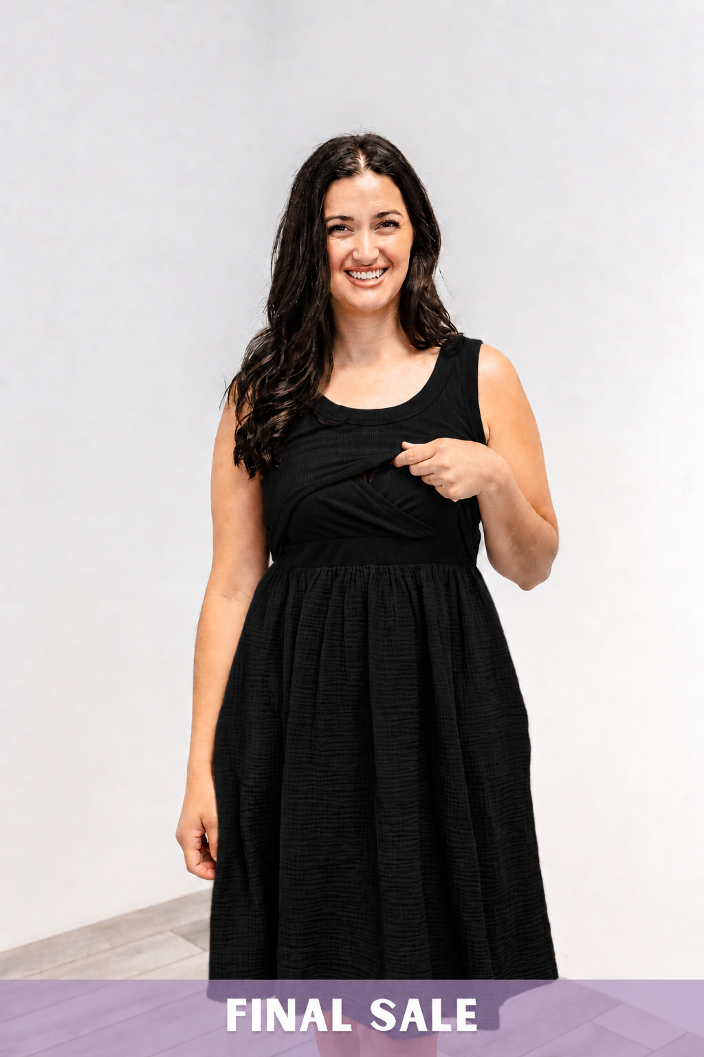 Woman showing the lift-up v-neck nursing access on the Latched Mama Breezy Cotton Nursing Dress in black.
