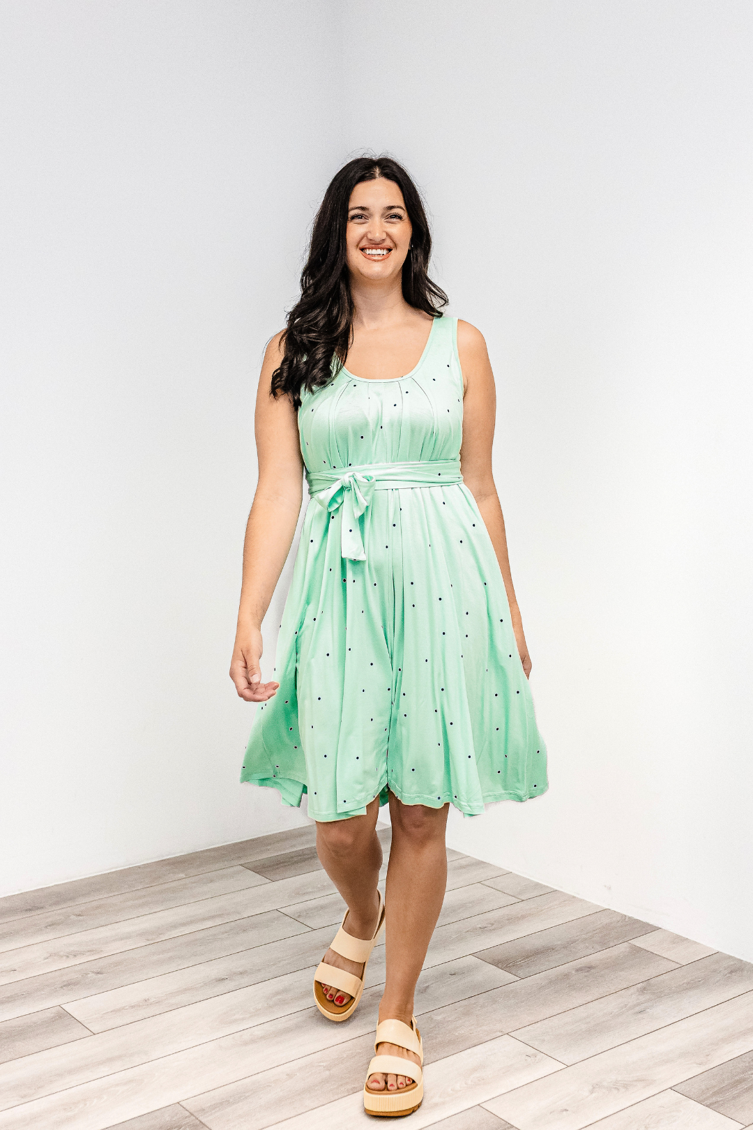 Woman wearing a polka dot "harbor mist" Latched Mama nursing romper momper with white sandals.