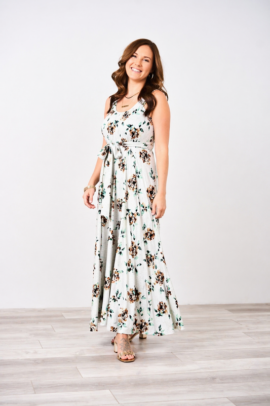 Woman wearing a white floral Latched Mama sleeveless nursing maxi momper with gold heels on a white background.