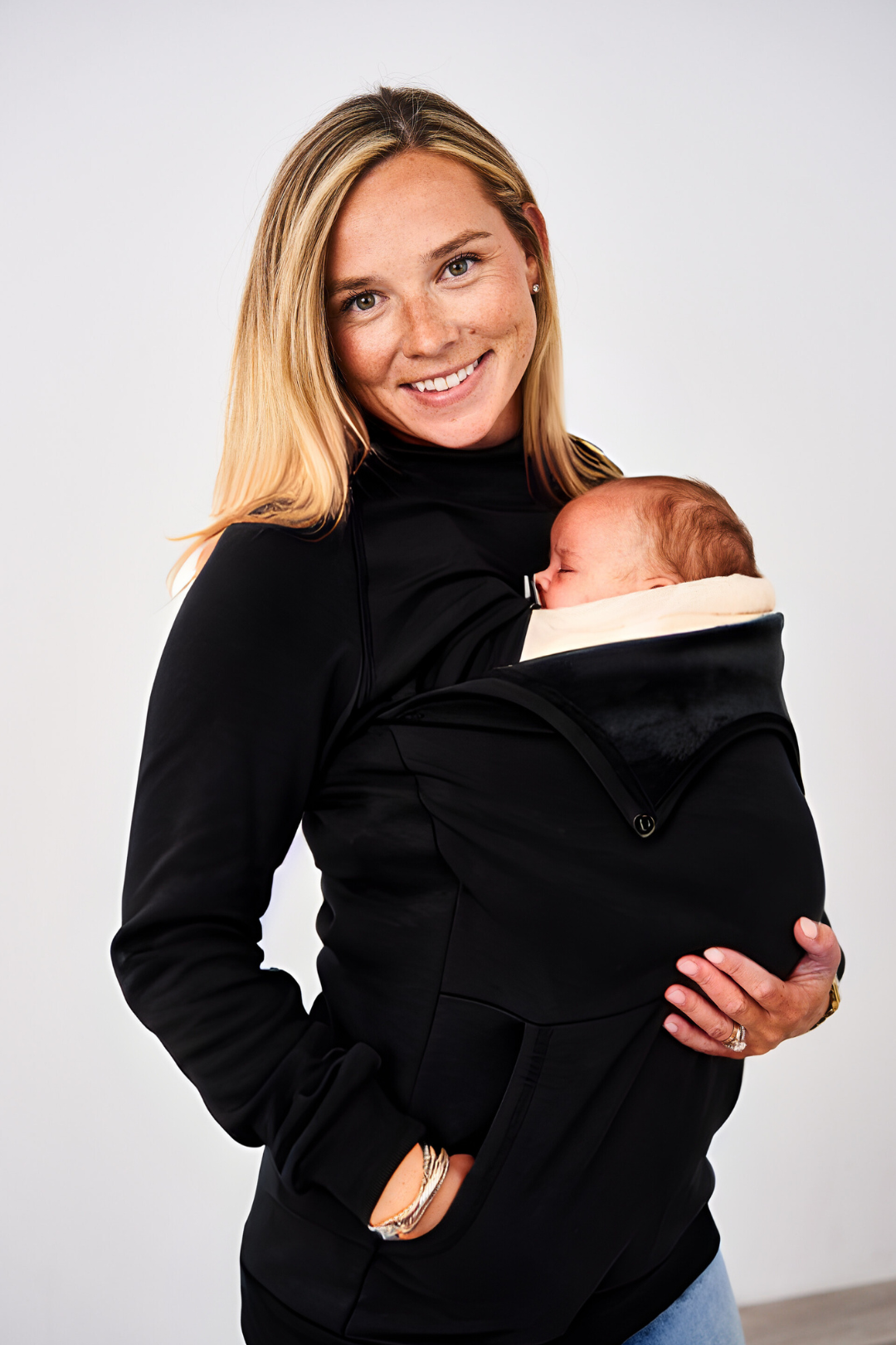 Woman babywearing an infant in a carrier with the Latched Mama Nursing Pullover on top