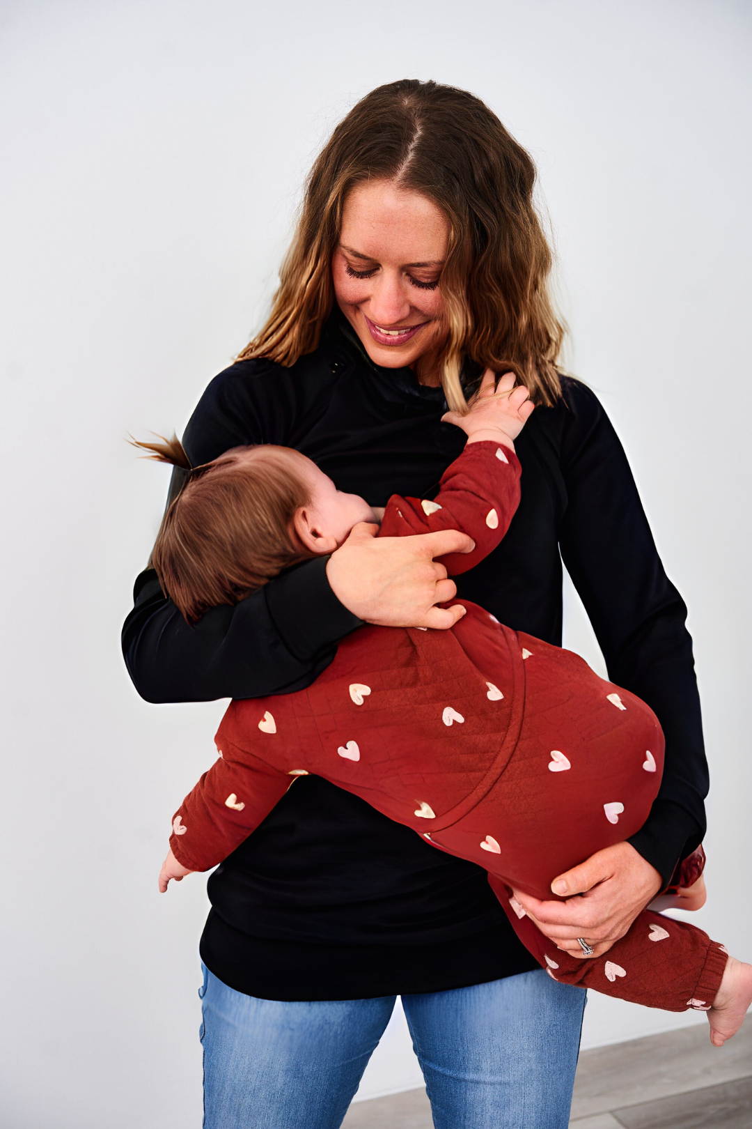 Woman nursing a baby in a Latched Mama Nursing Pullover in black