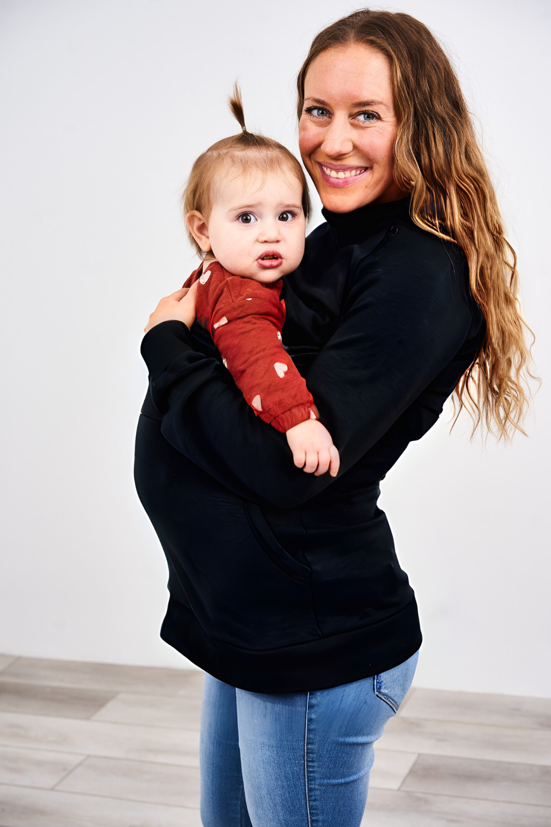 Mama wearing the Latched Mama Harbor Snap Nursing Pullover while carrying her baby in a front carrier