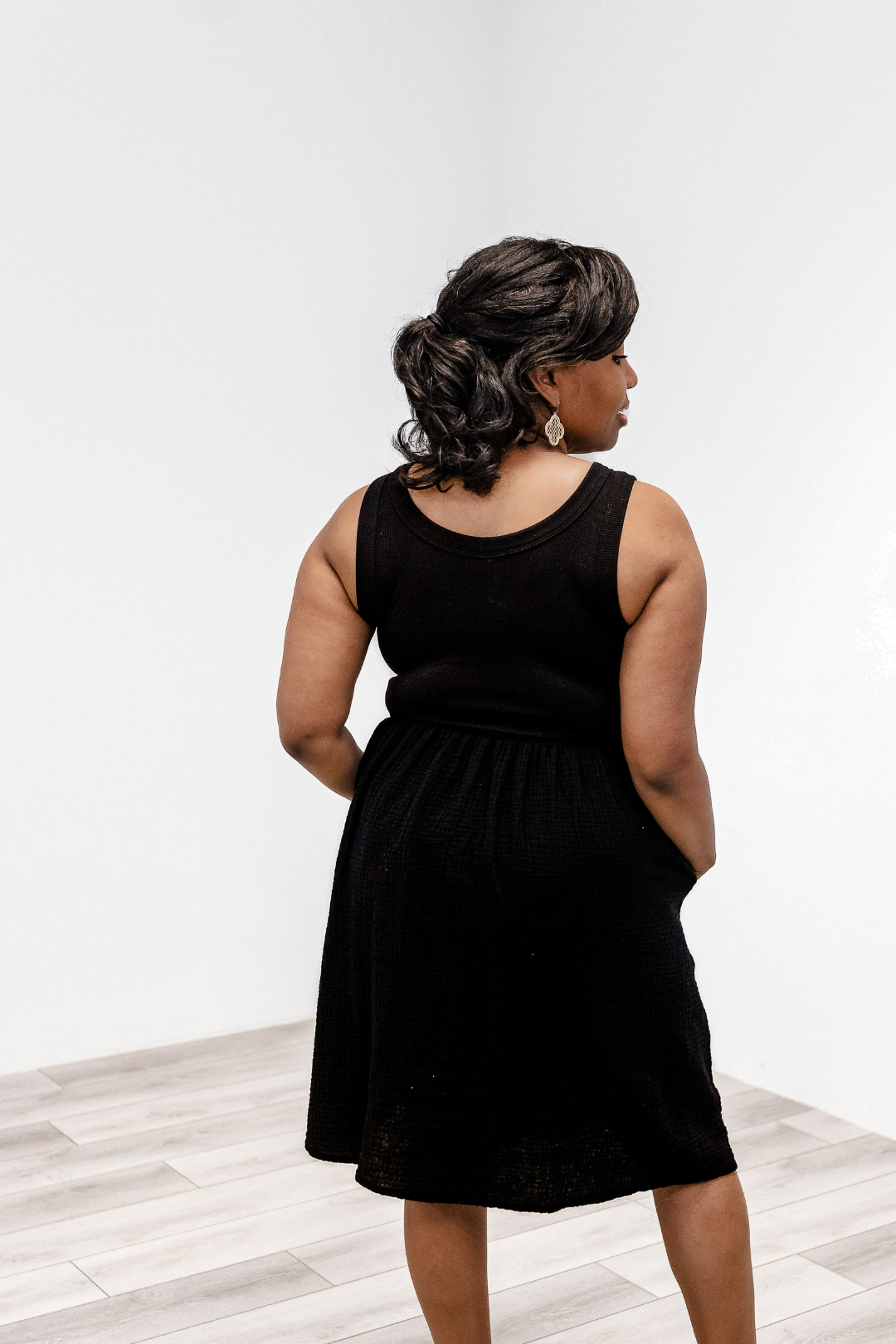Woman showing the back detail of the Latched Mama Breezy Cotton Nursing Dress in black.