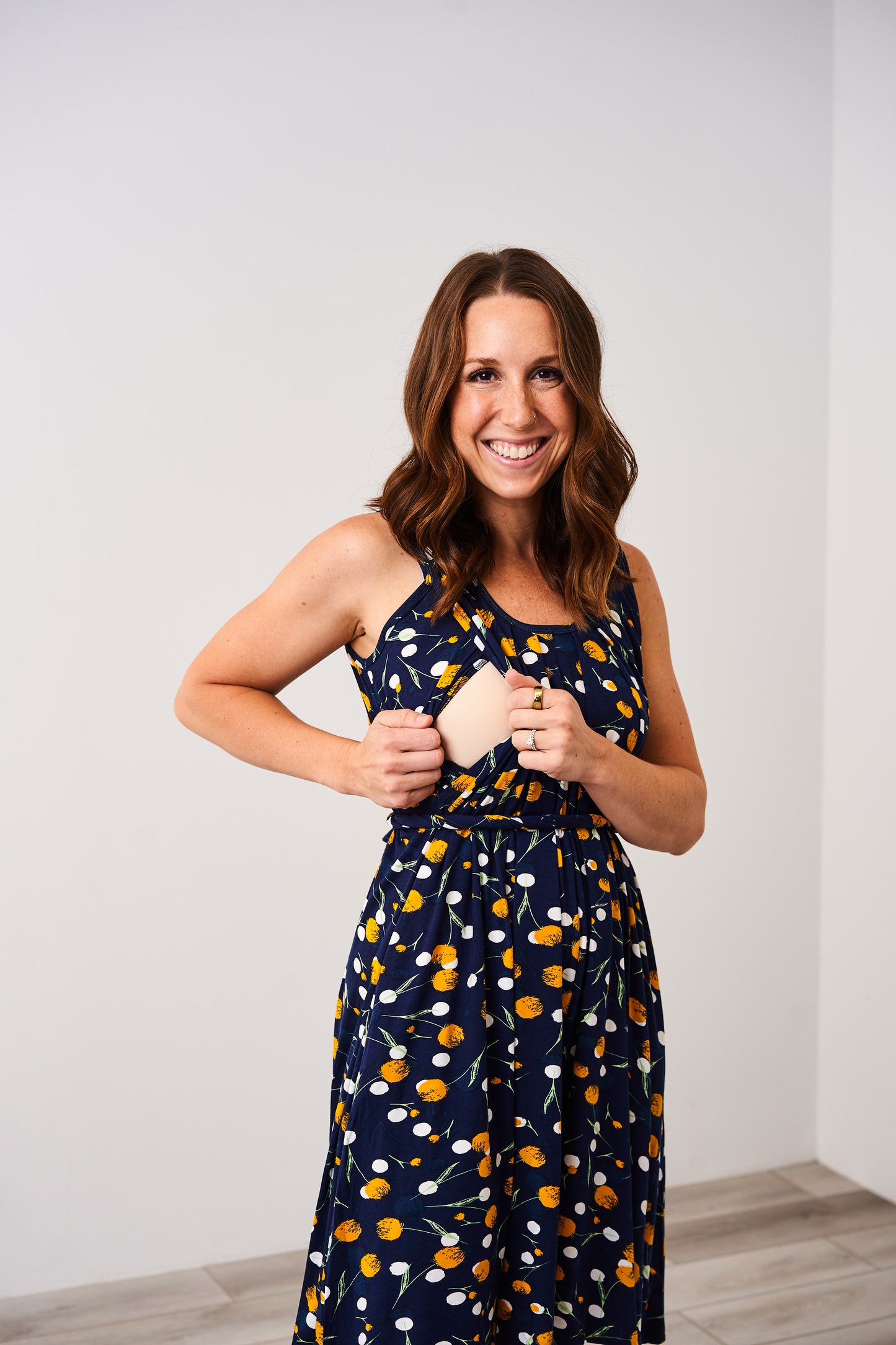 Woman wearing the Latched Mama Momper dandelion print sleeveless nursing romper against a white background