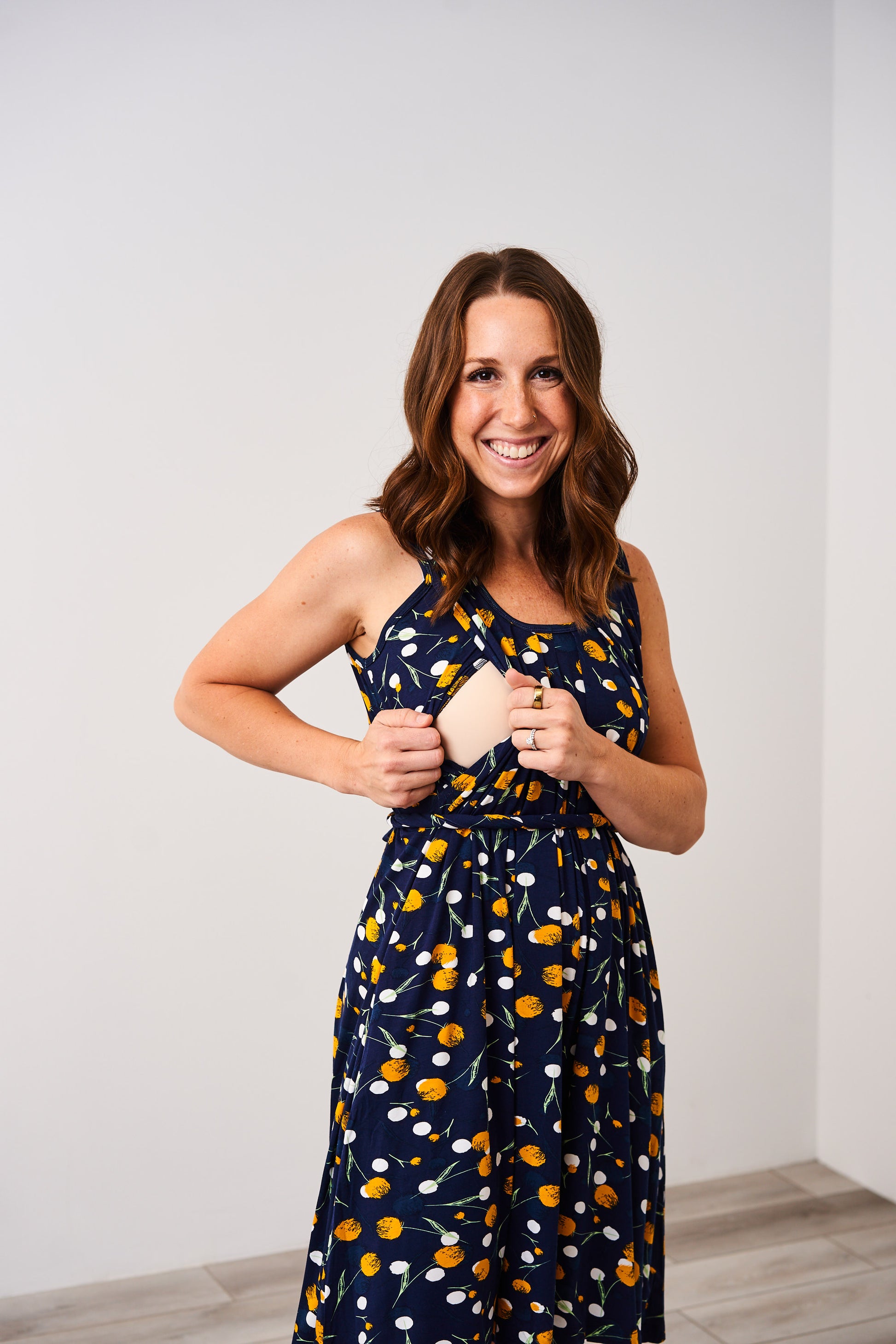 Woman wearing the Latched Mama Momper dandelion print sleeveless nursing romper against a white background