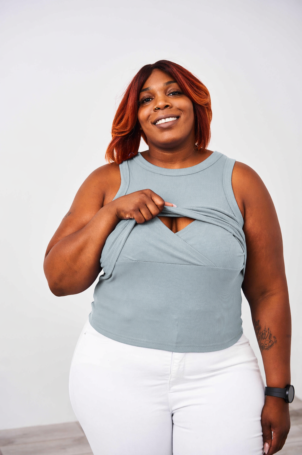 Woman wearing a Latched Mama Dusty Blue nursing ribbed tank top showing the easy one handed lift up nursing access.