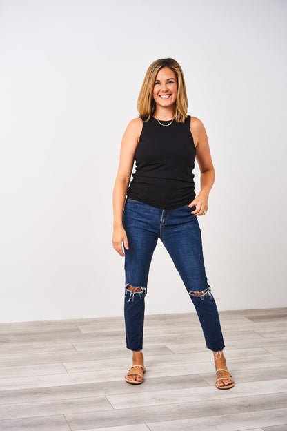 Woman wearing a black ribbed Latched Mama high neck nursing tank with blue jeans.