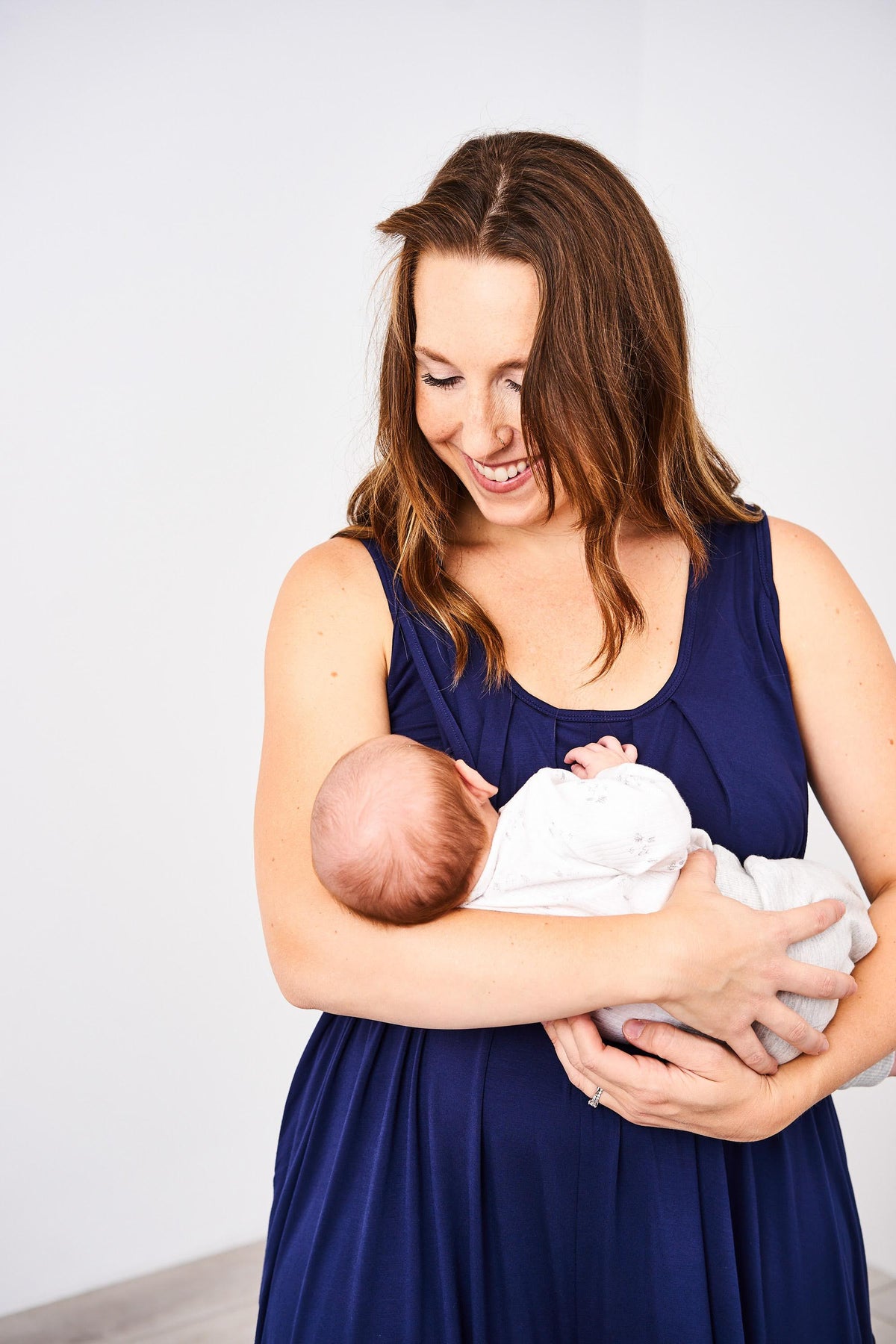 Woman breastfeeding a baby in the Latched Mama nursing Romper in the color Navy on a white background