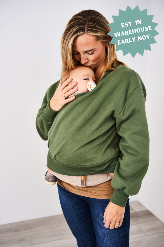 Woman wearing a green babywearing sweatshirt holding a baby against her chest.