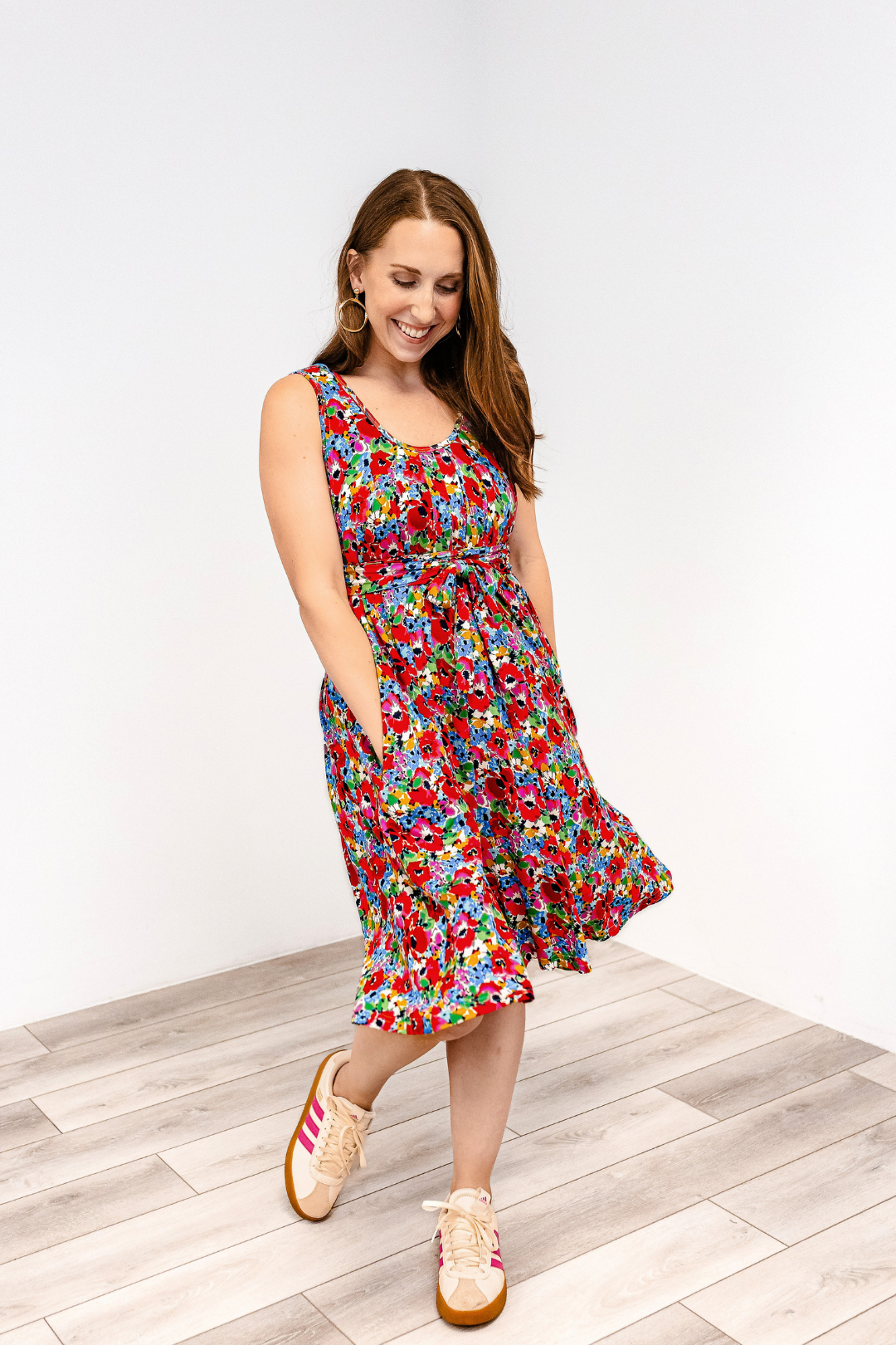 Woman wearing a colorful bloom burst latched mama nursing momper romper with sneakers.