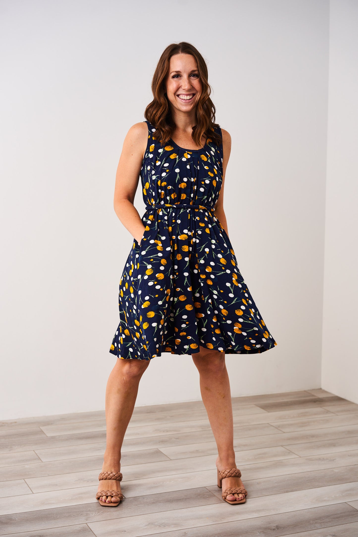 Woman wearing the Latched Mama Momper floral sleeveless nursing romper on a white background