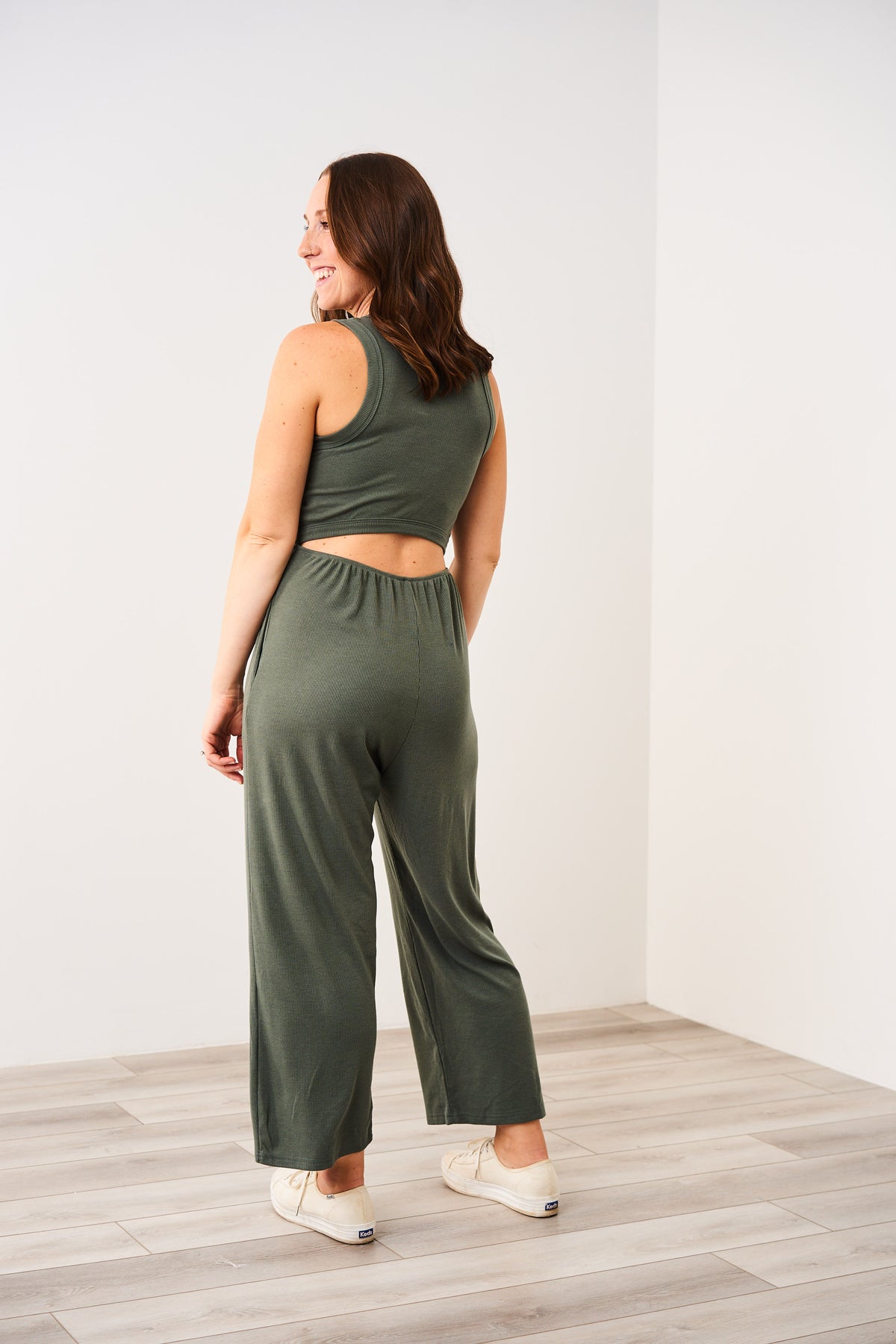 Woman showing the open back of the Latched Mama ribbed nursing jumper in green.