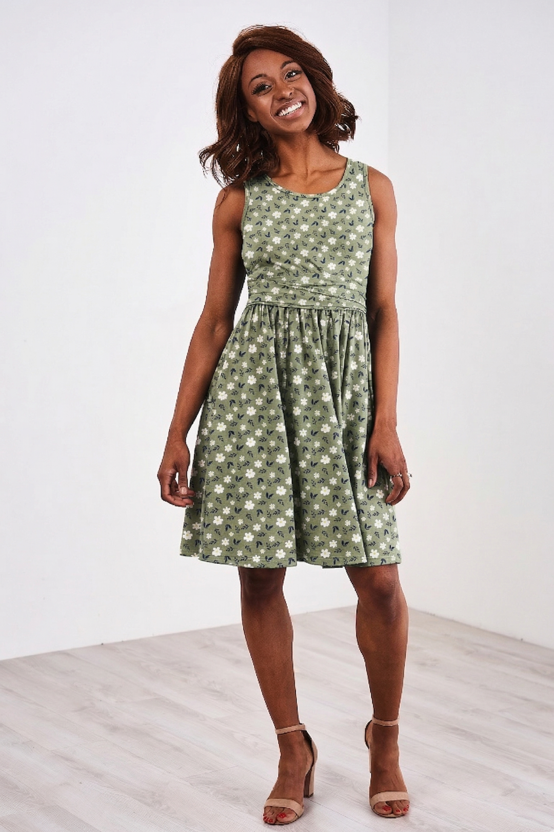 Woman wearing a Latched Mama green floral nursing dress with easy nursing access against a white background
