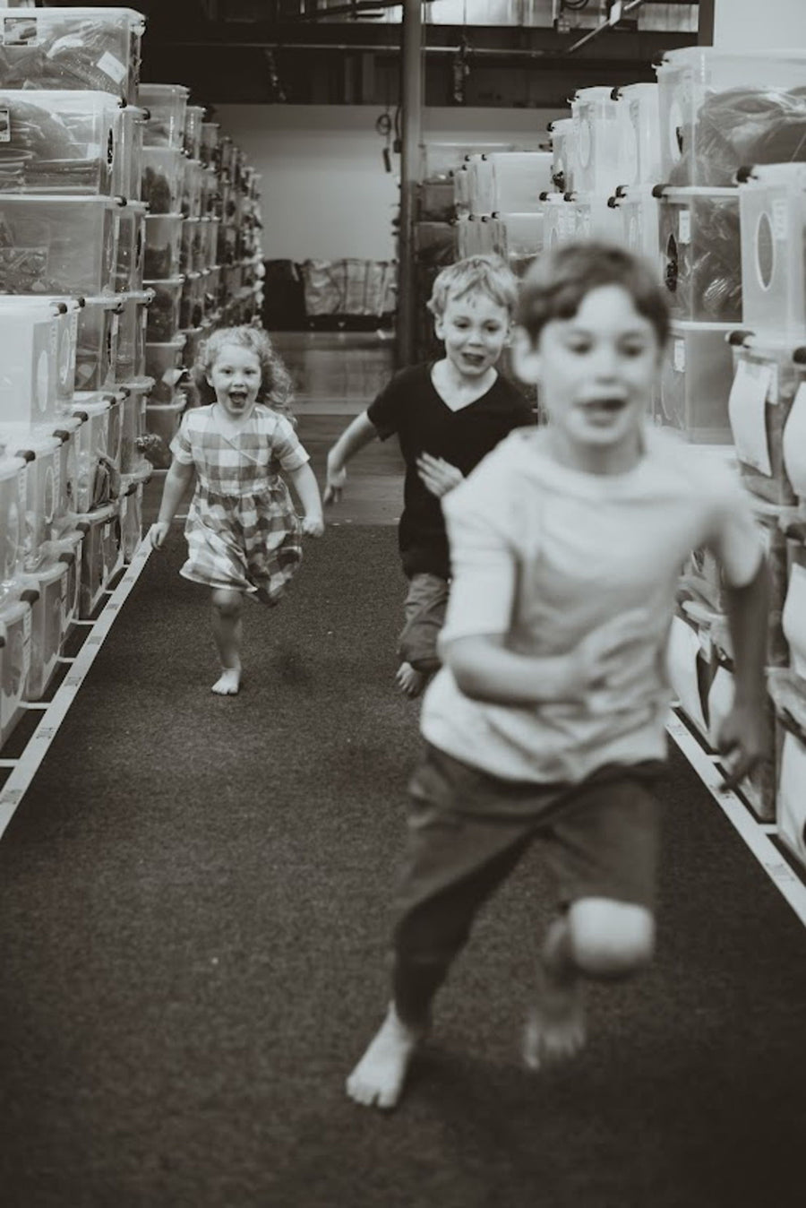 Children running between rows of inventory during the Latched Mama warehouse years