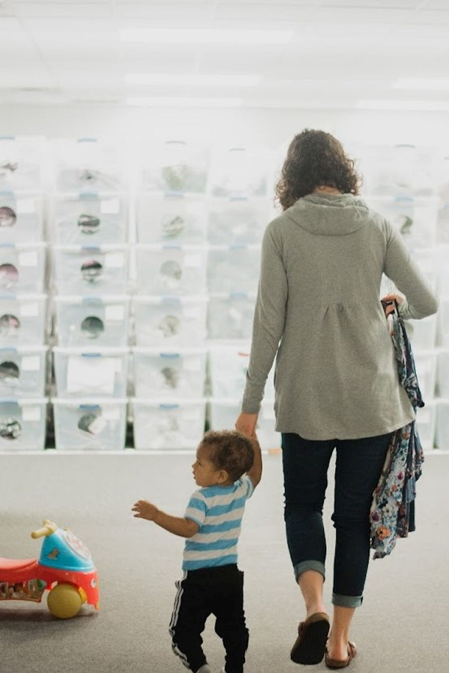 A mother holding her toddler’s hand as they walk through the former Latched Mama workplace