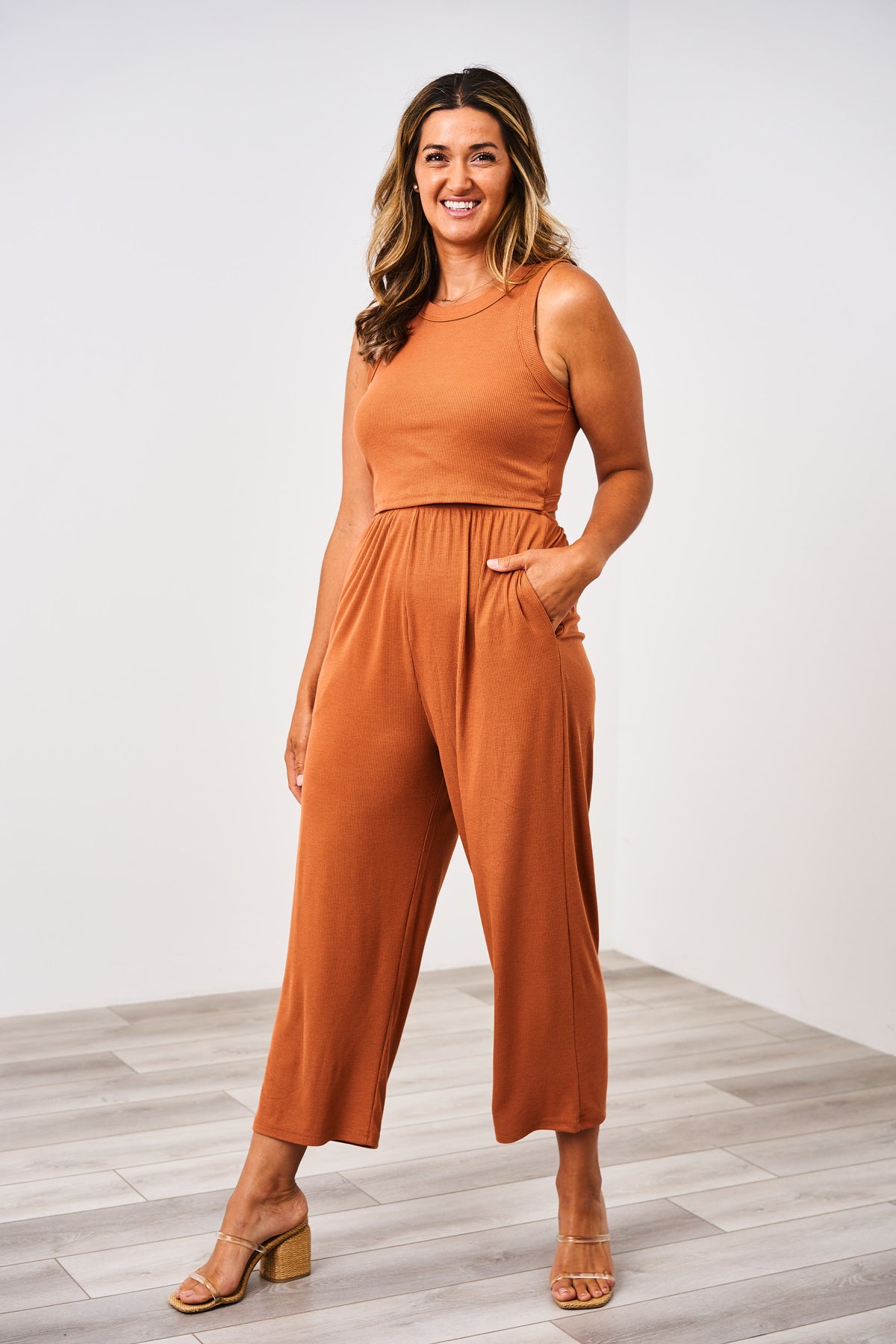 A woman wearing a copper Latched Mama ribbed nursing jumper with a high neck, elastic waist, and side pockets. The jumper is designed for nursing access.